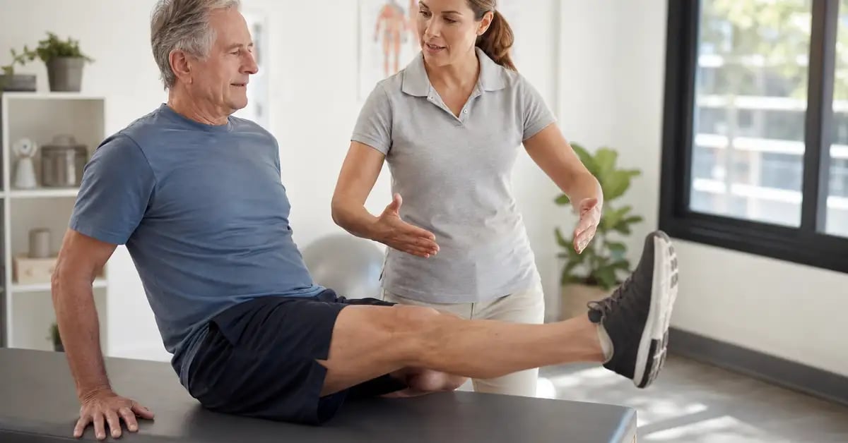 An older patient performing a straight-leg raise quadriceps-strengthening exercise under guidance of a CK Physio chartered physiotherapist