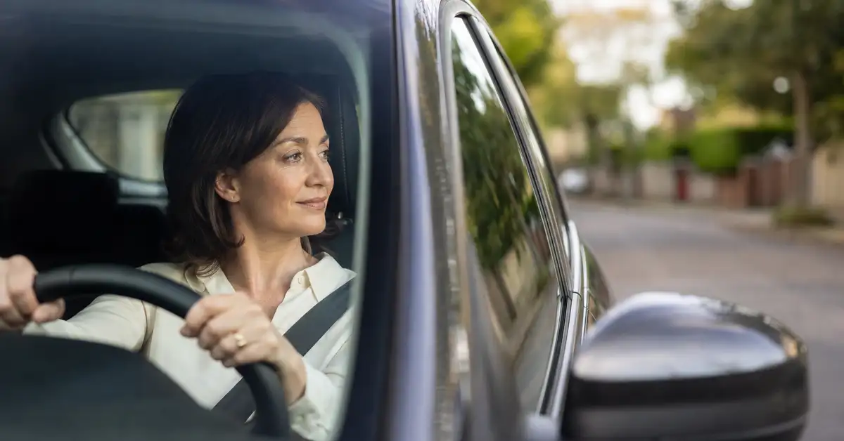 Adult woman driving confidently after completing a structured whiplash physiotherapy recovery programme in West London